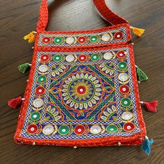 an embroidered bag with tassels and beads on the inside sits on a wooden surface