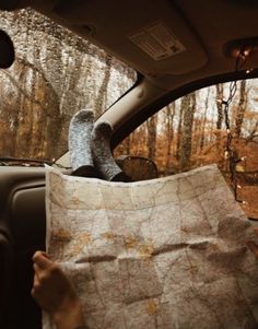 someone holding up a map in the back seat of a car