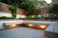 an outdoor seating area is lit up with lights in the center and surrounded by greenery