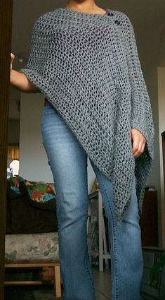 a woman is wearing a crocheted shawl and jeans