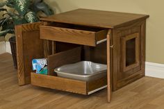 a wooden cabinet with a trash can in the bottom and an open drawer underneath it