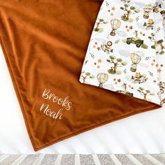 two baby blankets sitting next to each other on top of a bed