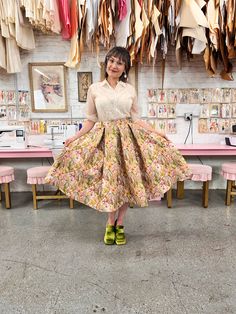 a woman is standing in front of a table with many clothes hanging on the wall