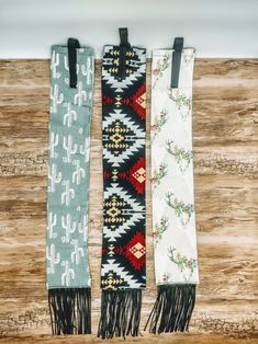 three scarfs hanging on a wooden wall, one with an antelope design