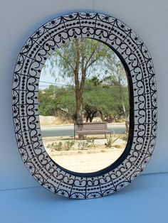 there is a mirror on the wall that has a bench in front of it and a tree