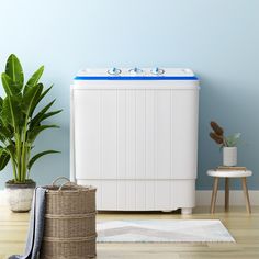 a white washing machine sitting next to a potted plant on top of a wooden floor