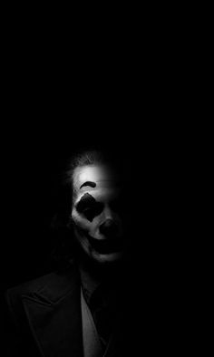 a man with his face painted white and wearing a clown mask, in the dark