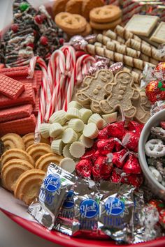 a red bowl filled with assorted candy and cookies