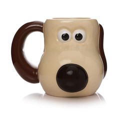 a brown and white dog shaped coffee mug with eyes on it's side, sitting in front of a white background