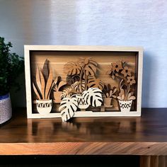 wooden cutout of houseplants and potted plants on a shelf next to a planter