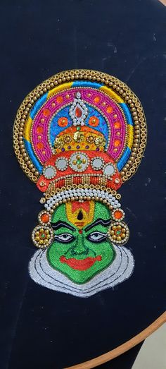 an artistic painting on a black surface with gold trimmings and colorful colors, depicting the face of lord rama