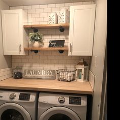 a washer and dryer in a small room with white cabinets on the wall