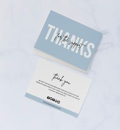 two business cards with the words thanks and thank you written in white ink on a light blue background