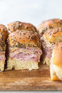 ham and cheese sliders cut in half on a cutting board with poppy seed sprinkles