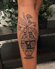 a woman's leg with a potted plant tattoo on it and flowers in the vase