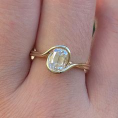 a woman's hand with a gold ring and an oval shaped diamond on it