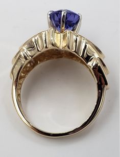 Title: Oval Tanzanite and Diamonds in 14 Kt Yellow Gold Ring Size 6. 1/2 US DesignerUnbranded MaterialYellow Gold 14Kt Stamped Style: Vintage Gemstone Details All measurements are approximate and may vary slightly from the listed dimensions. Diamonds: Cut: Round Diamonds 30 Estimated Size 1.8 mm and 1.5 mm average approximated 0.55 CTW Estimated Color: G-H Clarity: VS Tanzanite: 9.24 mm/7.04 mm/4.22 mm 1.93 CT Estimated Measurements Length/Width/Depth 20.52 mm/12.55 mm/8.47 mm Estimated Total We Exquisite Gold Sapphire Ring With Accent Stones, Exquisite Gold Multi-stone Sapphire Ring, Round Gold Gemstone With Center Stone, Gold Round Cut Gemstones Fine Jewelry, Unique Pear-shaped Gold Jewelry, Gold Oval Sapphire Ring For Collectors, Yellow Gold Marquise Cut Jewelry With Accent Stones, Gold Tanzanite Gemstone Rings, Gold Tanzanite Rings For Formal Occasions