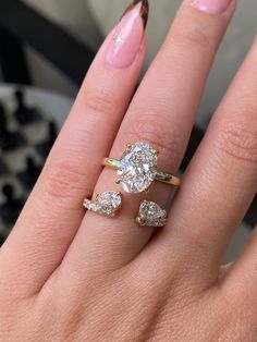 a woman's hand with two rings on it and one ring has three pear shaped diamonds