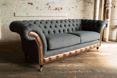 a grey couch sitting on top of a wooden floor next to a white brick wall