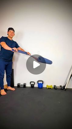 a man is holding a surfboard in his hand and standing on the floor next to some exercise equipment