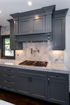 a kitchen with gray cabinets and marble counter tops