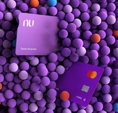 two purple and one orange credit cards surrounded by balls