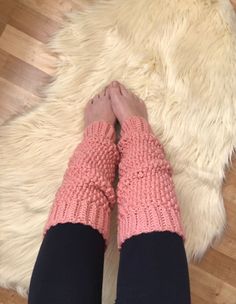 the legs of a woman wearing pink knitted gloves on top of a wooden floor