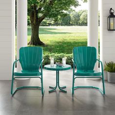 two teal chairs sitting on top of a patio next to a table under a tree