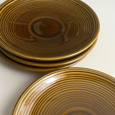 three yellow plates sitting on top of a white table next to each other with black lines