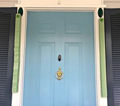 a blue front door with two black shutters and a gold handle on the side