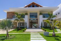 a large white house with palm trees in the front yard and steps leading up to it