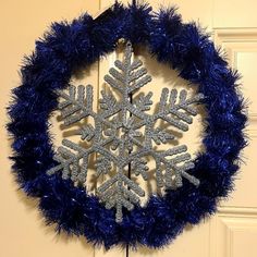 a snowflake ornament is hanging on a door with blue tinsel