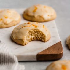 glazed cookies with orange icing on a cutting board