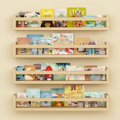 three wooden shelves with books on them against a beige wall, each holding different types of children's books