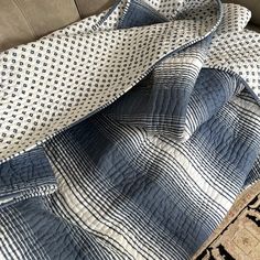 a blue and white quilted blanket laying on top of a couch