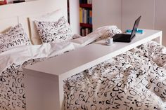 a laptop computer sitting on top of a bed covered in black and white comforters