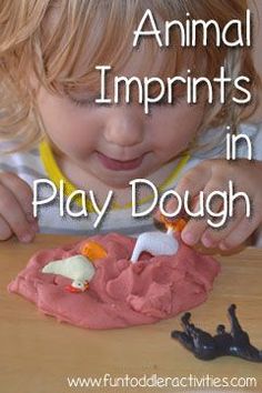 a young child is playing with play dough and plastic animals that are on the table