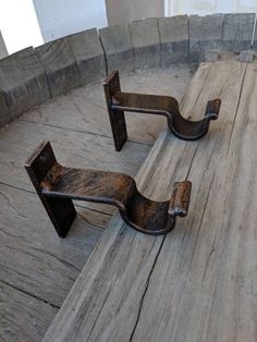 two metal brackets sitting on top of a wooden floor