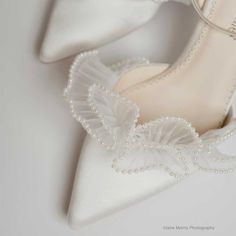 a pair of white shoes with pearls on them