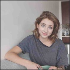 a woman sitting on a couch holding a green coffee cup and saucer in her hands