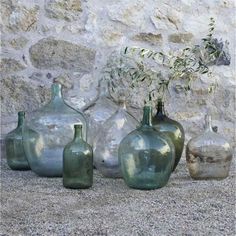 four green vases sitting next to each other in front of a stone wall