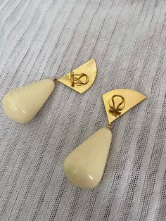 two pairs of yellow earrings sitting on top of a white cloth covered table next to a pair of scissors