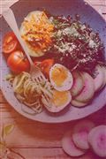 a bowl filled with lots of food on top of a wooden table next to sliced radishes