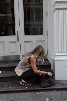 a woman kneeling down on the steps with her handbag in front of her face