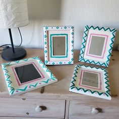 three frames sitting on top of a wooden table next to a lamp and a dresser