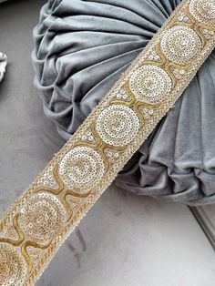 a close up of a gold and silver belt on top of a gray cloth bag