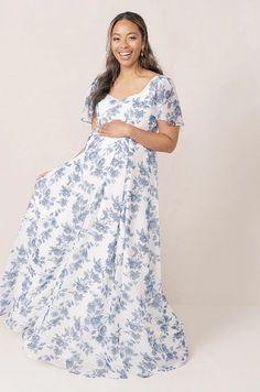 a pregnant woman in a blue and white floral print dress, smiling at the camera