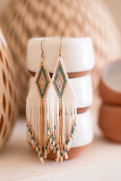 a pair of beaded earrings sitting on top of a white shelf next to other beads