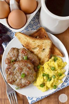 a plate with meatballs, eggs and scrambled eggs next to some bread on a table