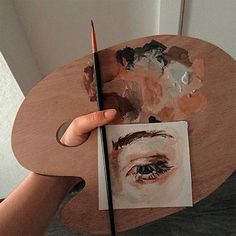 a person holding a paintbrush over a piece of paper with an image of a man's face on it